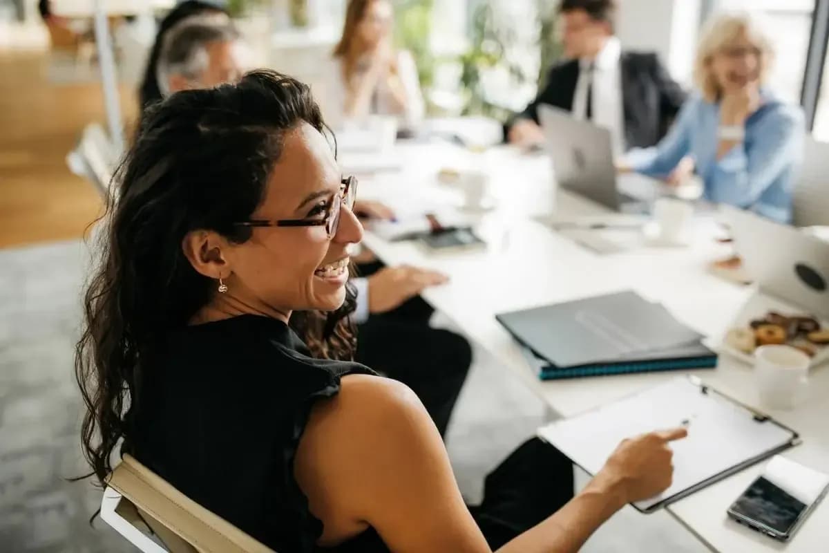Photo of a female millenial boss sitting at the desk with her collegues